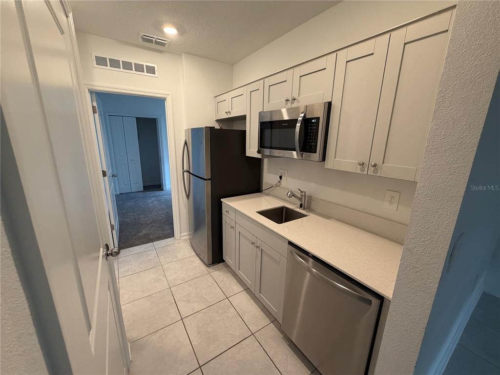 A small kitchen features light gray cabinets, stainless steel appliances, and white countertops — 314 LAWSON AVENUE UNIT Rear, HAINES CITY, FL