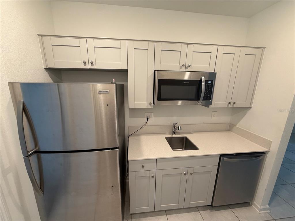 A kitchen features stainless steel appliances, light gray cabinets, and light-colored countertops — 314 LAWSON AVENUE UNIT Rear, HAINES CITY, FL
