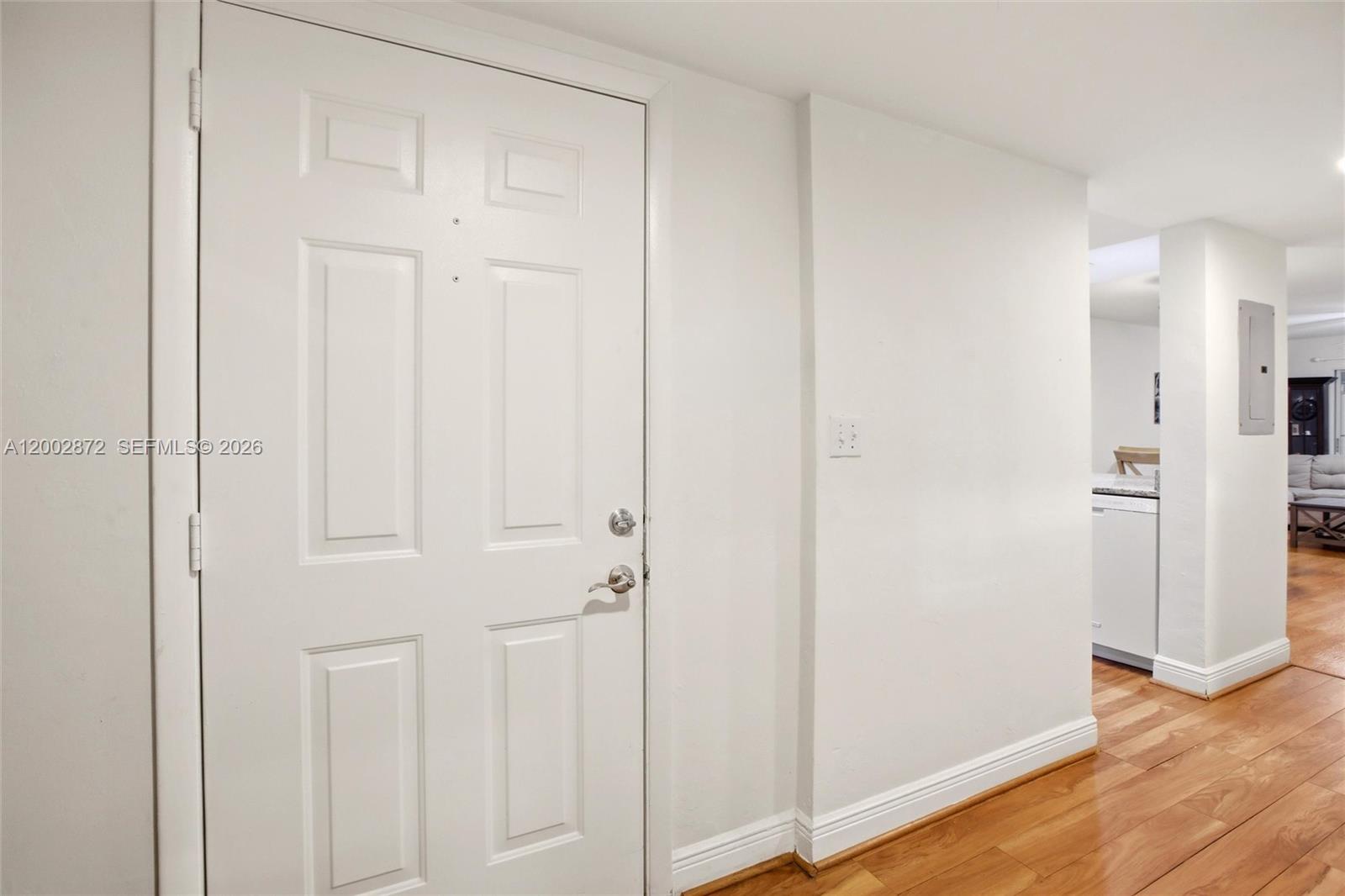 A white door stands next to a wall with a light switch and wood flooring — 338 Bradstrom Cir # 104, Naples FL 34113, NAPLES, FL