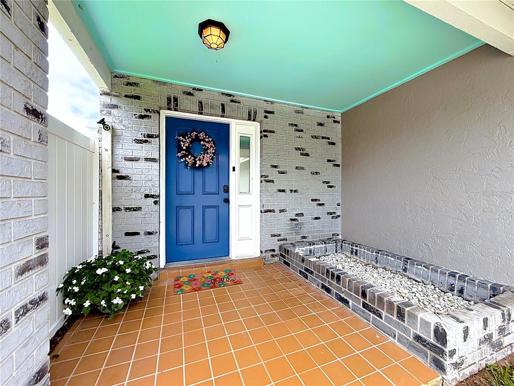 A front porch features a blue door, brick walls, a tiled floor, and a planter — 2908 BRIDGEGATE COURT, ORLANDO, FL