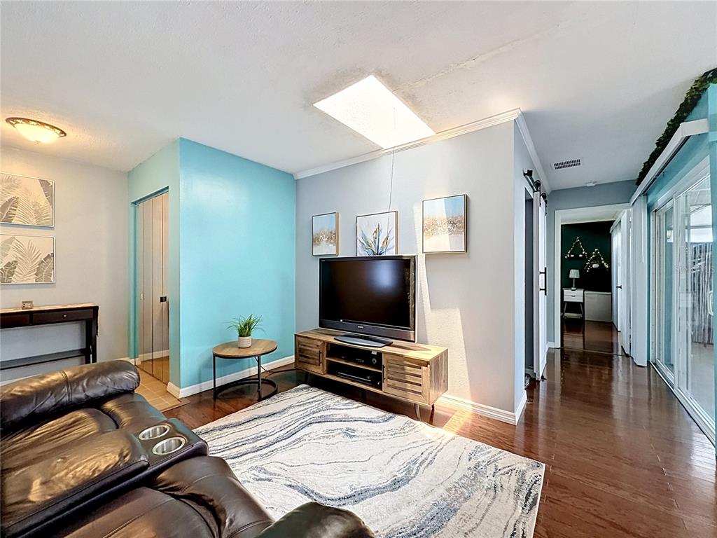 A living room features a television on a wooden stand, a rug, and blue walls — 2908 BRIDGEGATE COURT, ORLANDO, FL