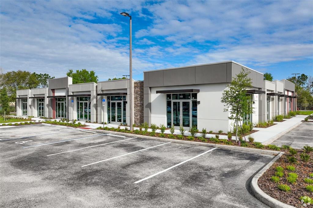 A modern, single-story commercial office building with glass-front entrances and an adjacent asphalt parking lot — 13504 VILLAGE PARK DRIVE UNIT 103, ORLANDO, FL