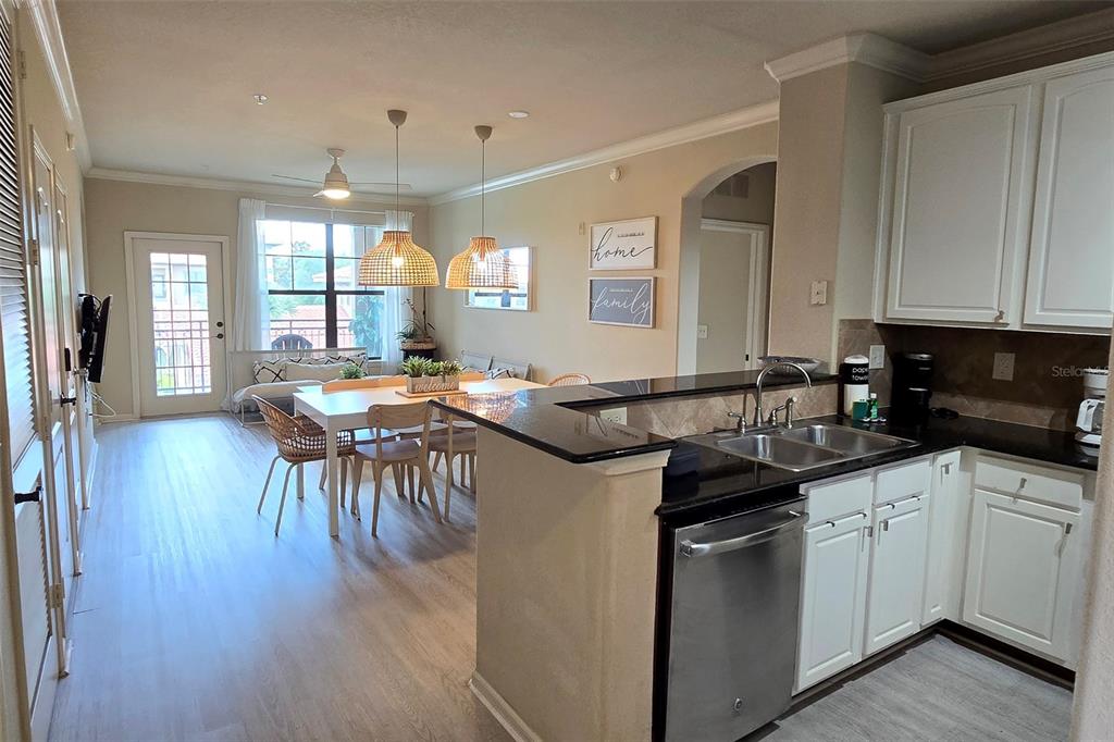 A kitchen with white cabinets and black countertops overlooks a dining area with pendant lights — 912 CHARO PARKWAY UNIT 233, DAVENPORT, FL