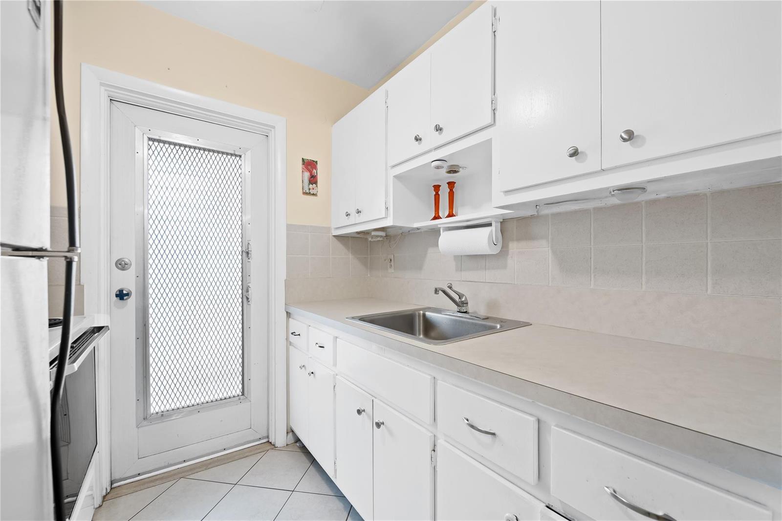 A kitchen features white cabinets, a stainless steel sink, and a door with a screen — 2750 W Golf Boulevard # 233, Pompano Beach FL 33064, POMPANO BEACH, FL