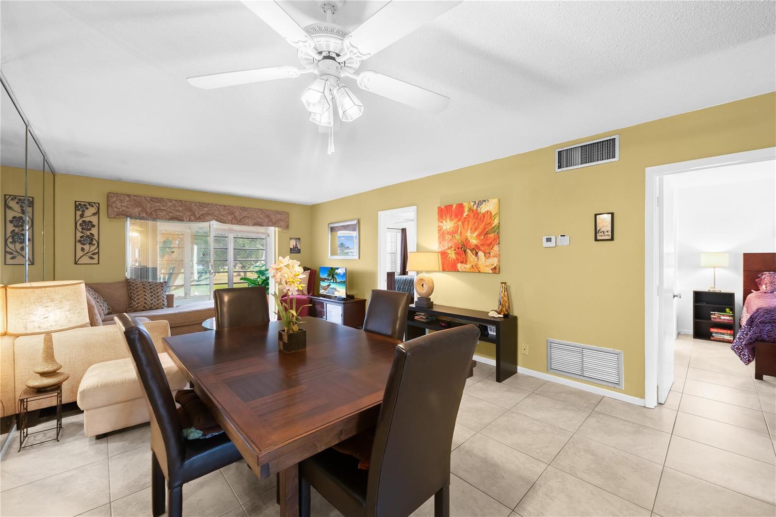 A dining area with a wooden table and chairs sits in front of a living room — 2750 W Golf Boulevard # 233, Pompano Beach FL 33064, POMPANO BEACH, FL