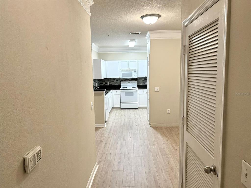 A hallway leads to a kitchen featuring white cabinets, white appliances, and light wood-look flooring — 8842 VILLA VIEW CIRCLE UNIT 3, ORLANDO, FL