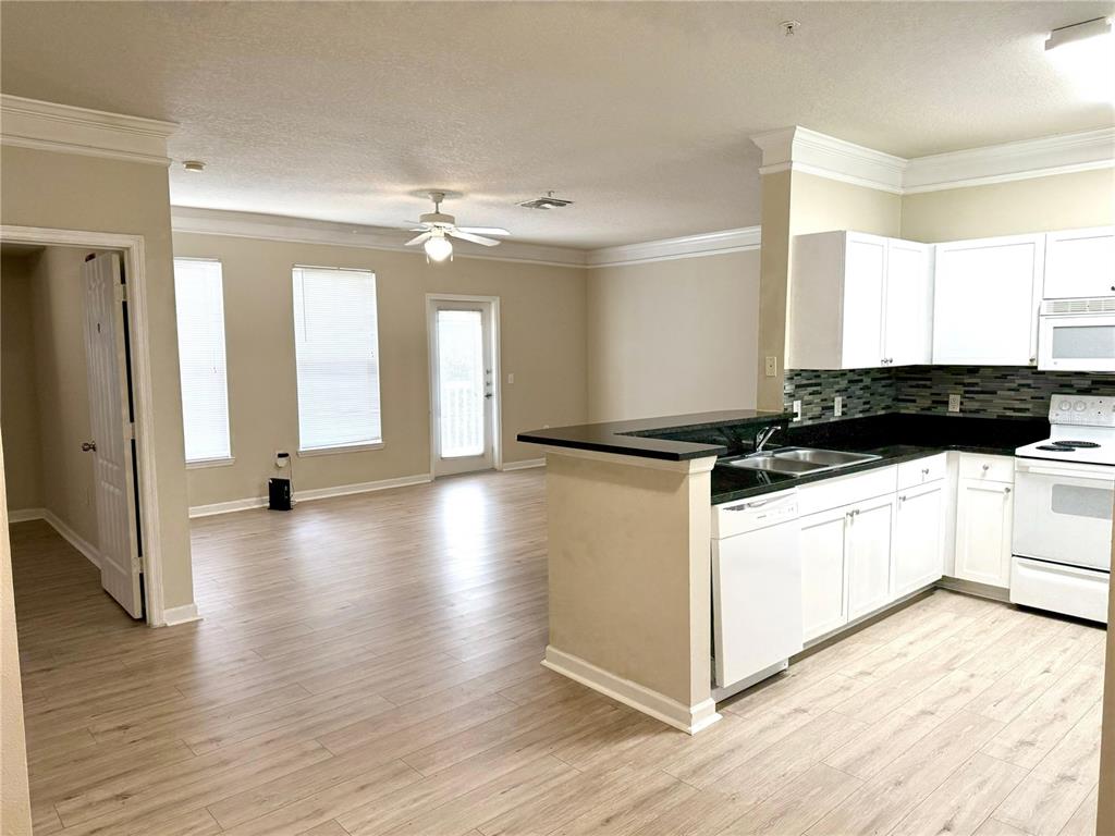 An open-concept kitchen with white cabinets and a living area with wood-look flooring — 8842 VILLA VIEW CIRCLE UNIT 3, ORLANDO, FL