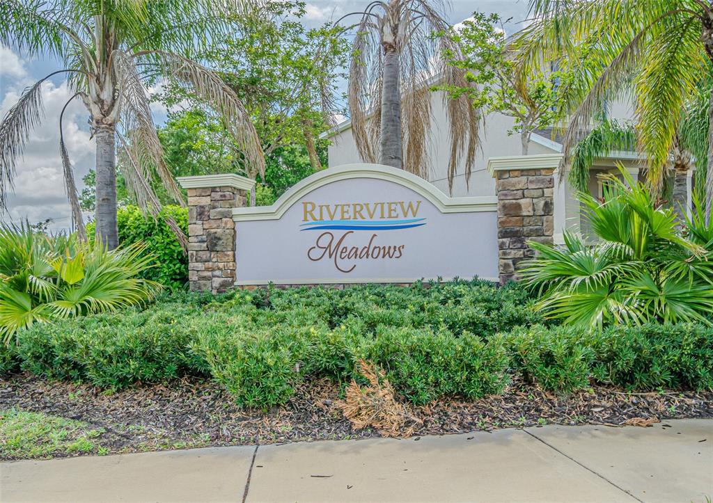 A stone-pillared monument sign for Riverview Meadows stands in front of landscaping and palm trees — 10627 SCENIC HOLLOW DRIVE, RIVERVIEW, FL