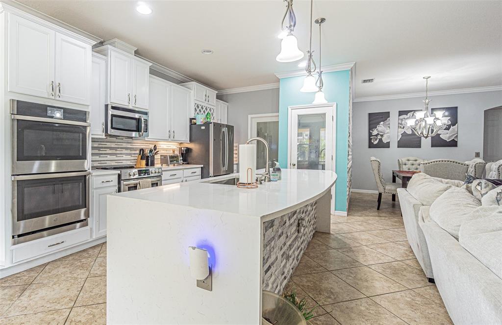 A kitchen features white cabinets, a large quartz island, and a dining area nearby — 10627 SCENIC HOLLOW DRIVE, RIVERVIEW, FL