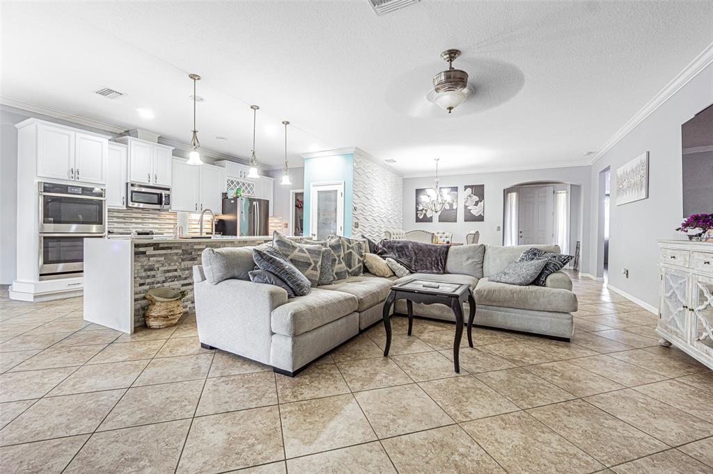 A spacious open-concept living room and kitchen featuring tile floors and a large sectional sofa — 10627 SCENIC HOLLOW DRIVE, RIVERVIEW, FL