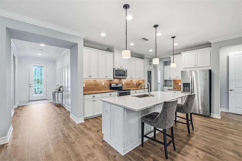 A kitchen with white cabinets, a granite-topped island, and wood-look flooring — 31321 DRISCOLL DRIVE, WESLEY CHAPEL, FL