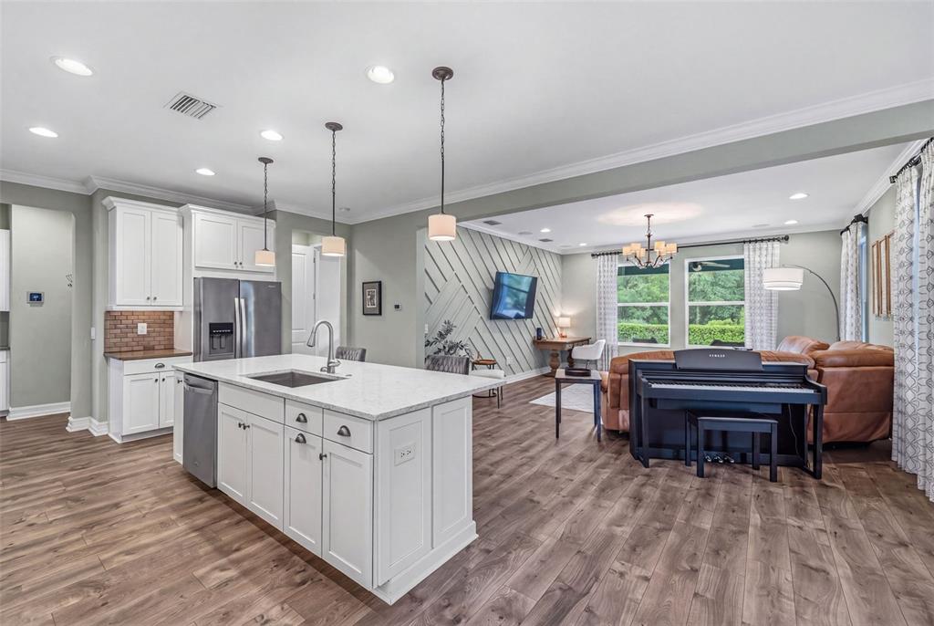 A kitchen with a white island and stainless steel appliances opens into a living area — 31321 DRISCOLL DRIVE, WESLEY CHAPEL, FL