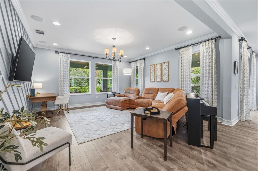 A living room features light blue walls, a brown sectional sofa, and wood-look flooring — 31321 DRISCOLL DRIVE, WESLEY CHAPEL, FL