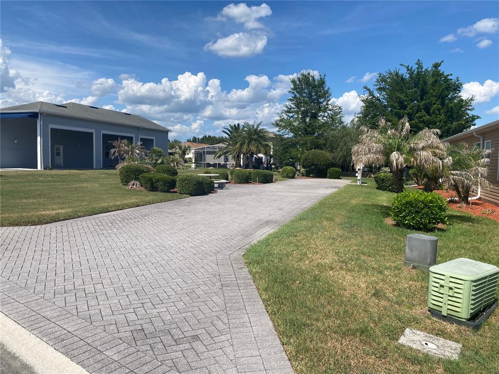 A paved driveway leads toward a house with a large garage under a blue sky — 357 TRAVELERS DRIVE, POLK CITY, FL