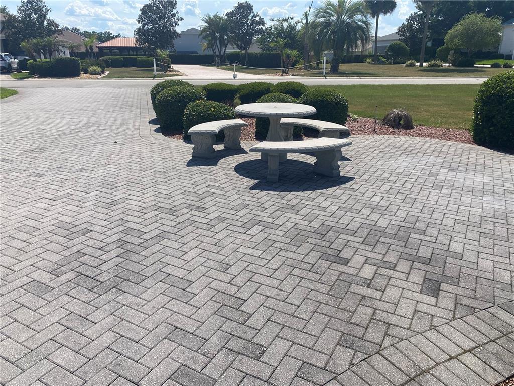 A stone patio features a circular table with matching curved benches surrounded by landscaping — 357 TRAVELERS DRIVE, POLK CITY, FL
