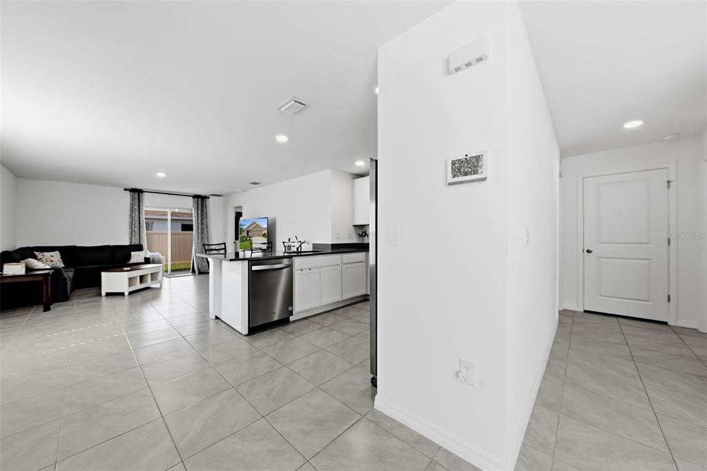 A kitchen with white cabinets and stainless steel appliances opens into a living room area — 37396 SHARKS EYE LANE, ZEPHYRHILLS, FL