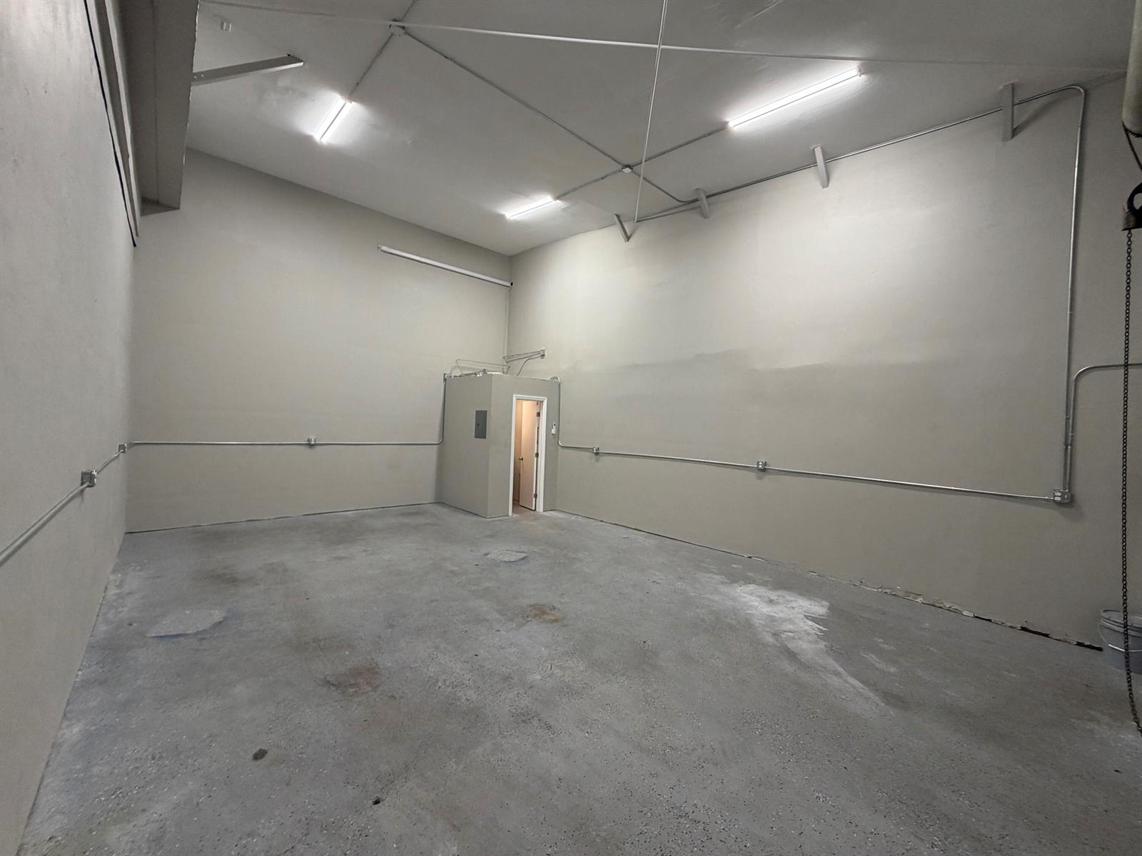 An empty industrial space features concrete floors, high ceilings, exposed conduit, and a small room — 1173b SW 1st Way, Deerfield Beach FL 33441, DEERFIELD BEACH, FL