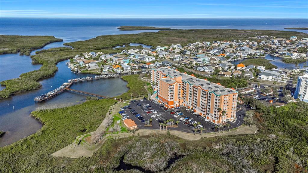 An aerial view shows a large orange apartment building surrounded by mangroves and water — 4516 SEAGULL DRIVE UNIT 313, NEW PORT RICHEY, FL