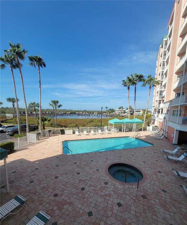 An outdoor swimming pool and hot tub are situated on a patio beside a building — 4516 SEAGULL DRIVE UNIT 313, NEW PORT RICHEY, FL