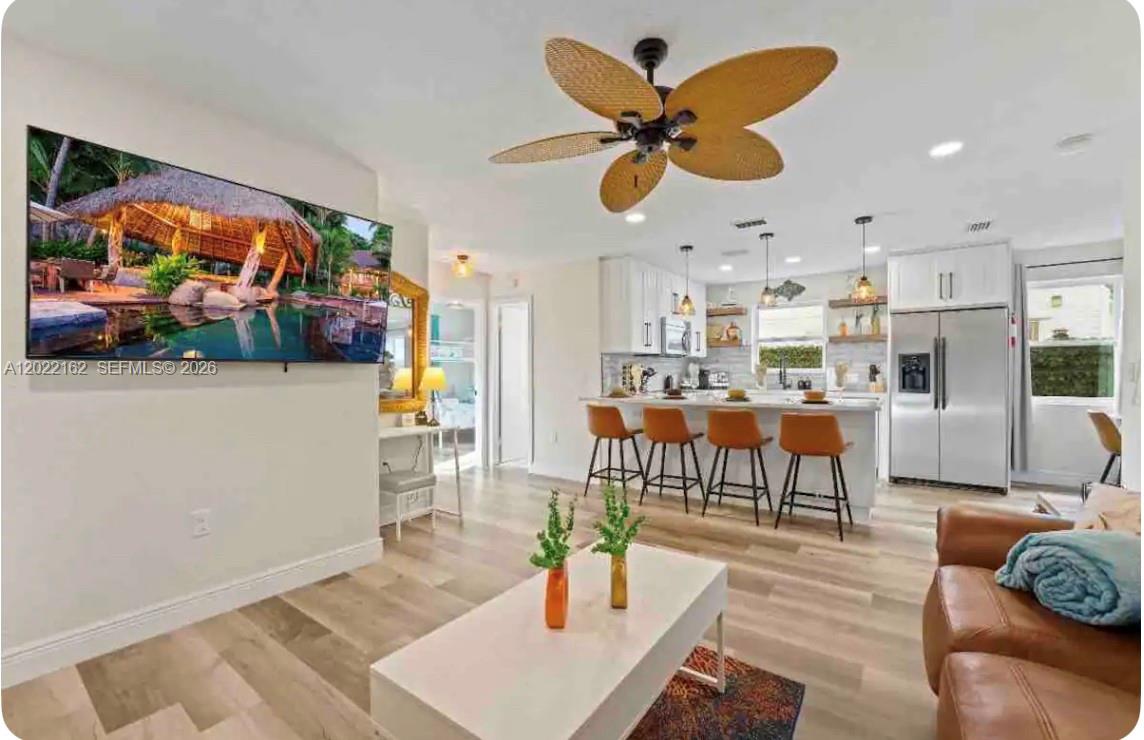 An open-concept living room and kitchen featuring a ceiling fan, island seating, and wood flooring — 301 N Hollywood Ave, Daytona FL 32118, DAYTONA, FL