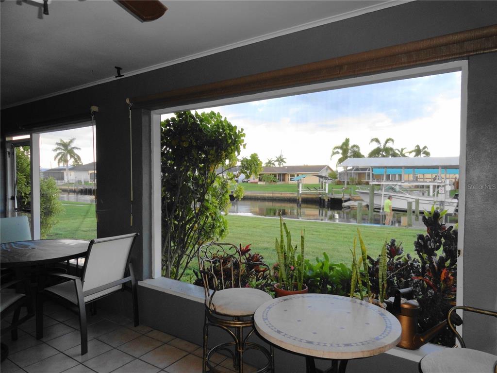 A screened-in patio features a dining set and overlooks a canal with a boat dock — 5226 NEVILLE TERRACE, PORT CHARLOTTE, FL