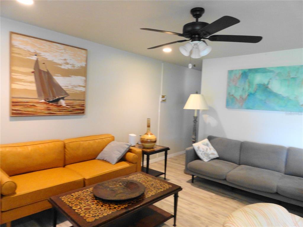 A living room features a yellow sofa, a gray sofa, and two large wall paintings — 5226 NEVILLE TERRACE, PORT CHARLOTTE, FL