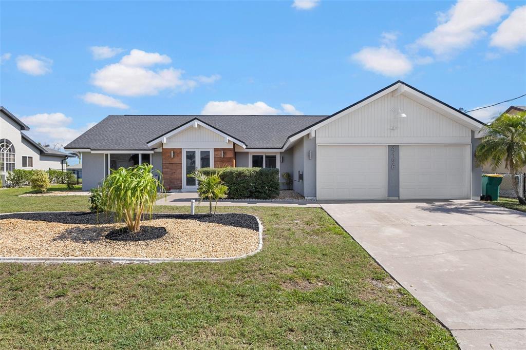 A single-story house with a gray exterior, white garage doors, and a landscaped front yard — 4196 EASTLAKE COURT, PORT CHARLOTTE, FL