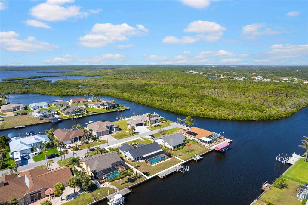 An aerial view shows waterfront houses with pools along a canal surrounded by dense vegetation — 4196 EASTLAKE COURT, PORT CHARLOTTE, FL