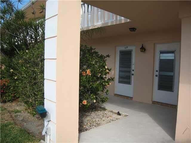 A covered concrete walkway leads to two white doors with glass panels on a building — 2115 NE 42nd Court # 109n, Lighthouse Point FL 33064, LIGHTHOUSE POINT, FL