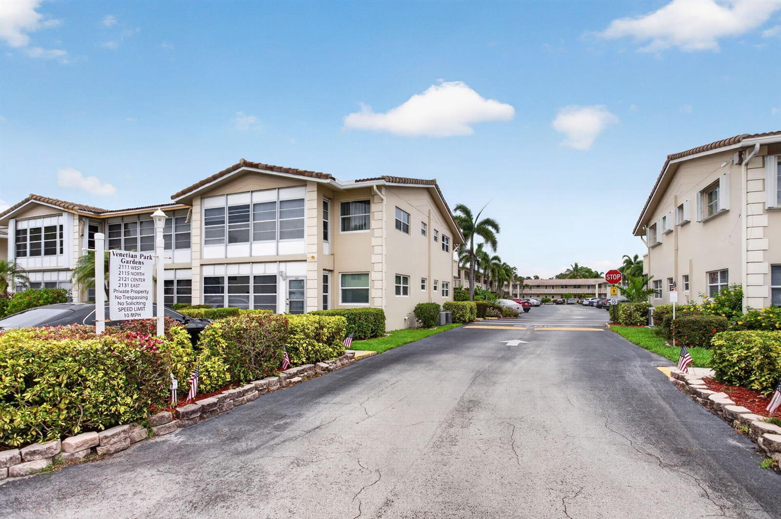 An exterior view of a multi-story apartment complex with a paved driveway and landscaped bushes — 2115 NE 42nd Court # 109n, Lighthouse Point FL 33064, LIGHTHOUSE POINT, FL