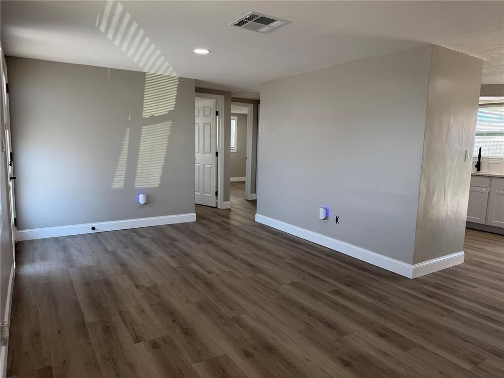 An interior view of a room with gray walls, wood-look flooring, and white trim — 7220 FOX HOLLOW DRIVE, PORT RICHEY, FL