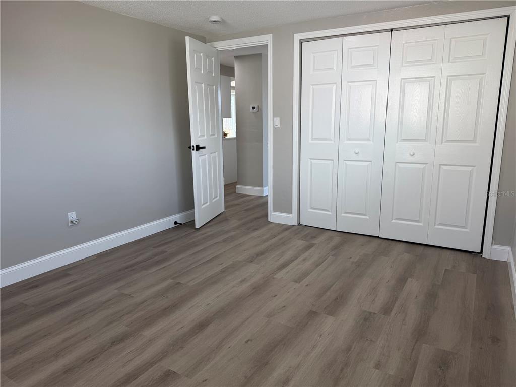 A bedroom with gray walls, wood-look flooring, and white bi-fold closet doors — 7220 FOX HOLLOW DRIVE, PORT RICHEY, FL