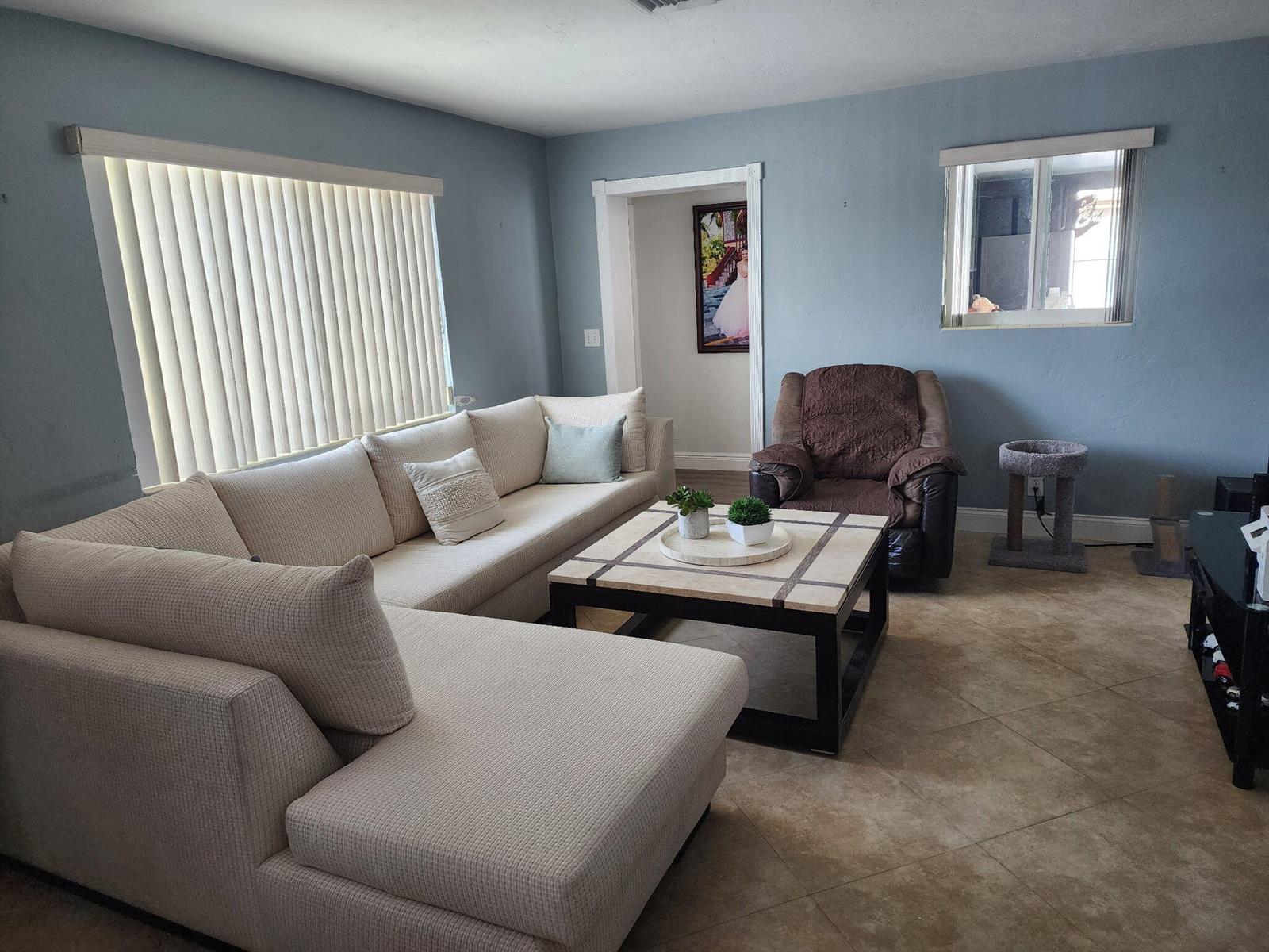 A living room features a large beige sectional sofa, a square coffee table, and blue walls — 2016 Kenwood Road, West Palm Beach FL 33409, WEST PALM BEACH, FL