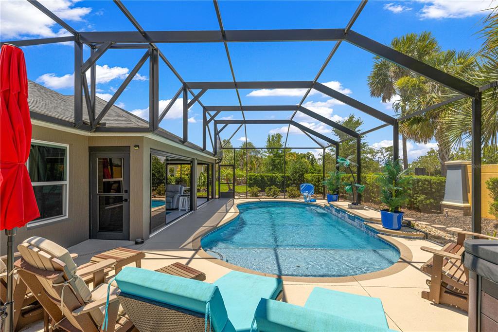 A screened-in patio features a swimming pool, lounge chairs, and a view of the yard — 1116 MAYNARD PATH, THE VILLAGES, FL