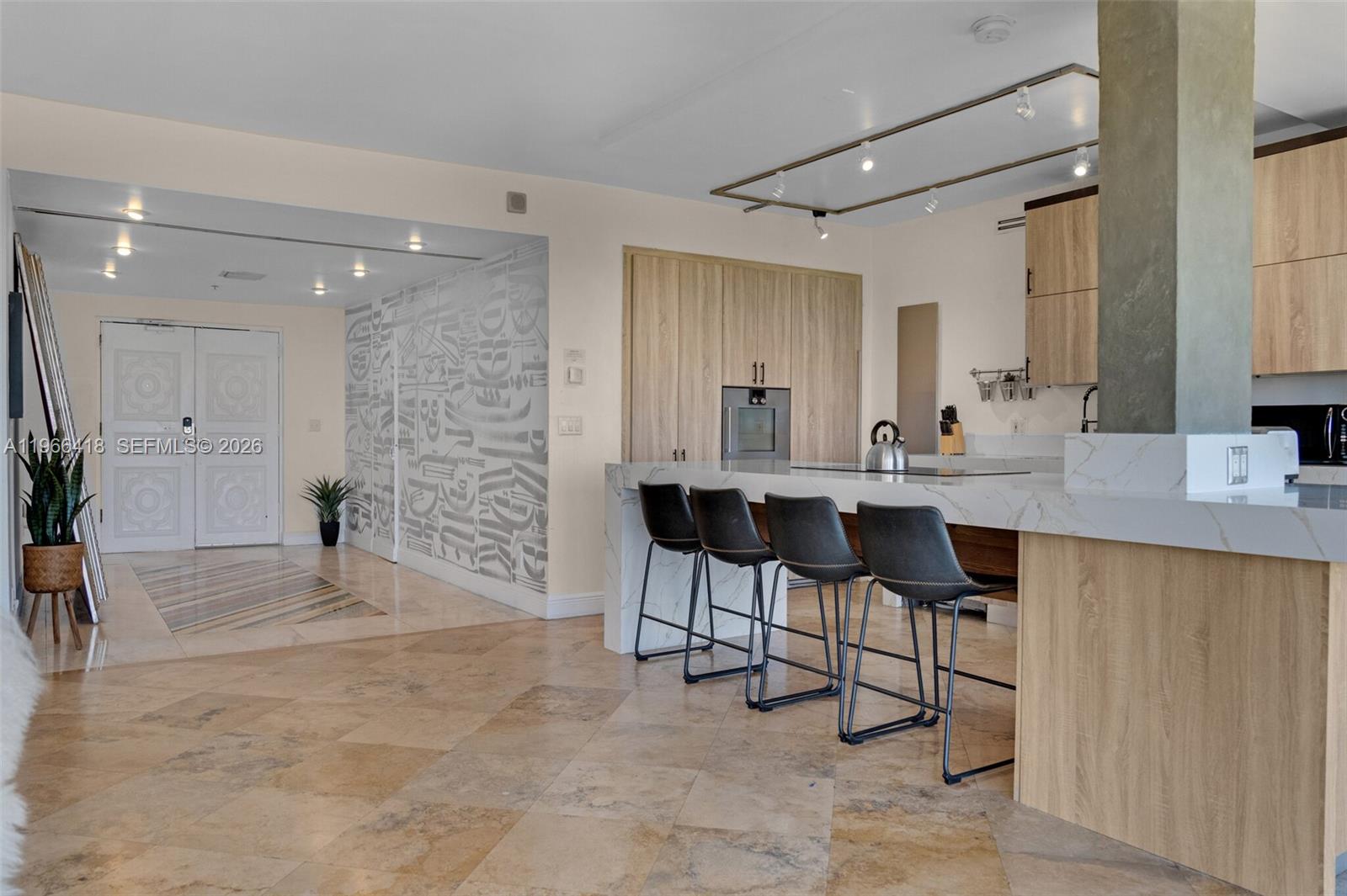 A modern kitchen features a large marble-topped island with bar stools and light wood cabinetry — 5781 Biscayne Blvd # 3, Miami FL 33137, MIAMI, FL