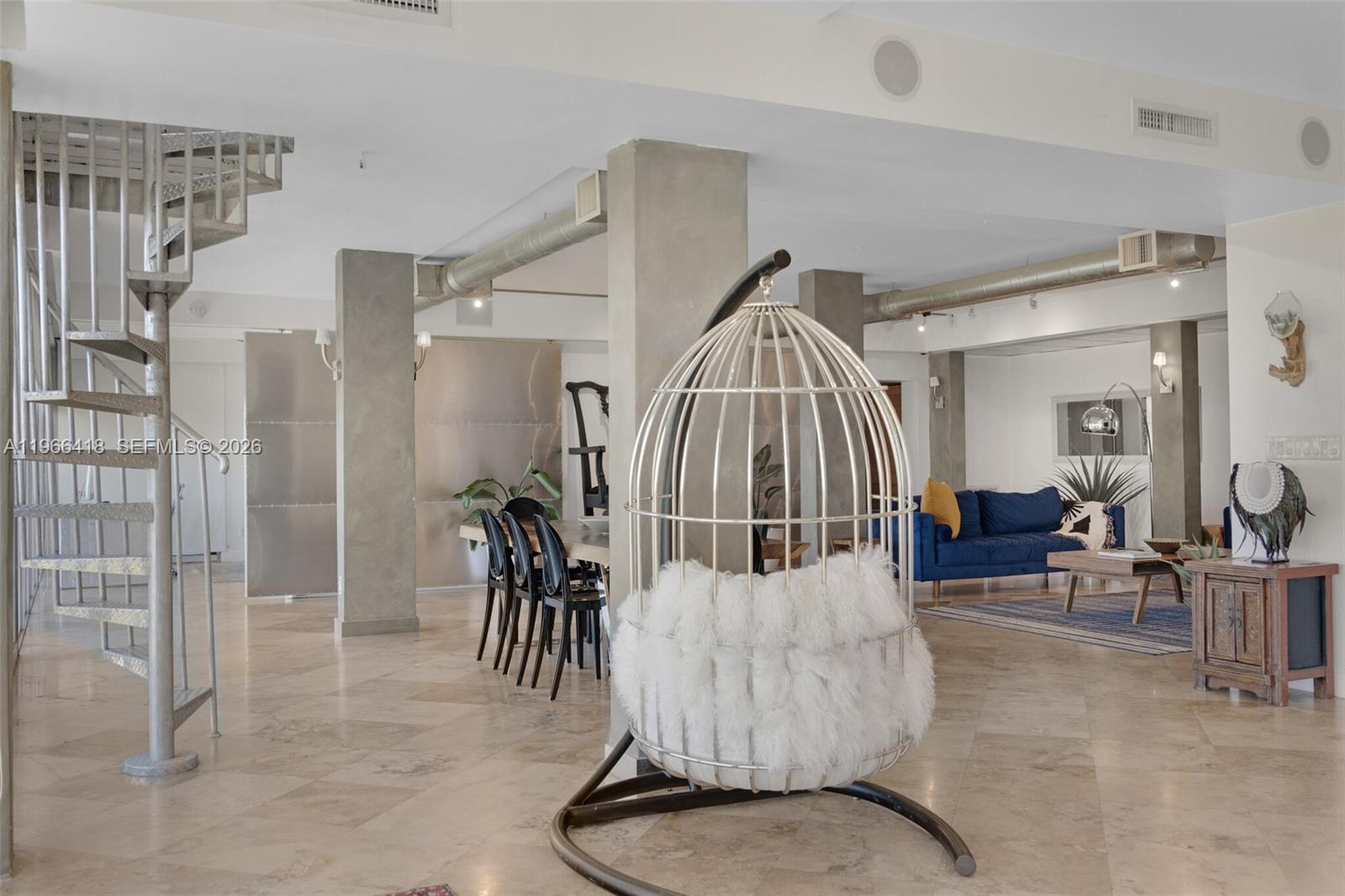 An open-concept living and dining area features a spiral staircase, concrete columns, and tiled floors — 5781 Biscayne Blvd # 3, Miami FL 33137, MIAMI, FL