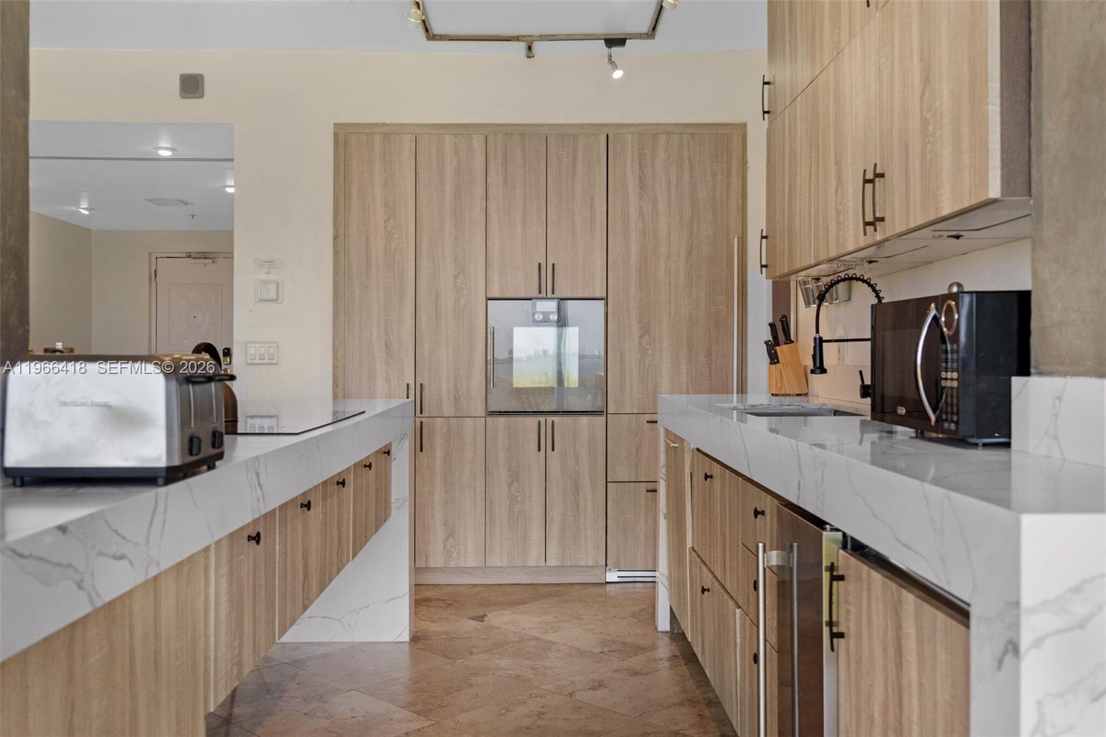 A modern kitchen features light wood cabinetry, white marble countertops, and stainless steel appliances — 5781 Biscayne Blvd # 3, Miami FL 33137, MIAMI, FL
