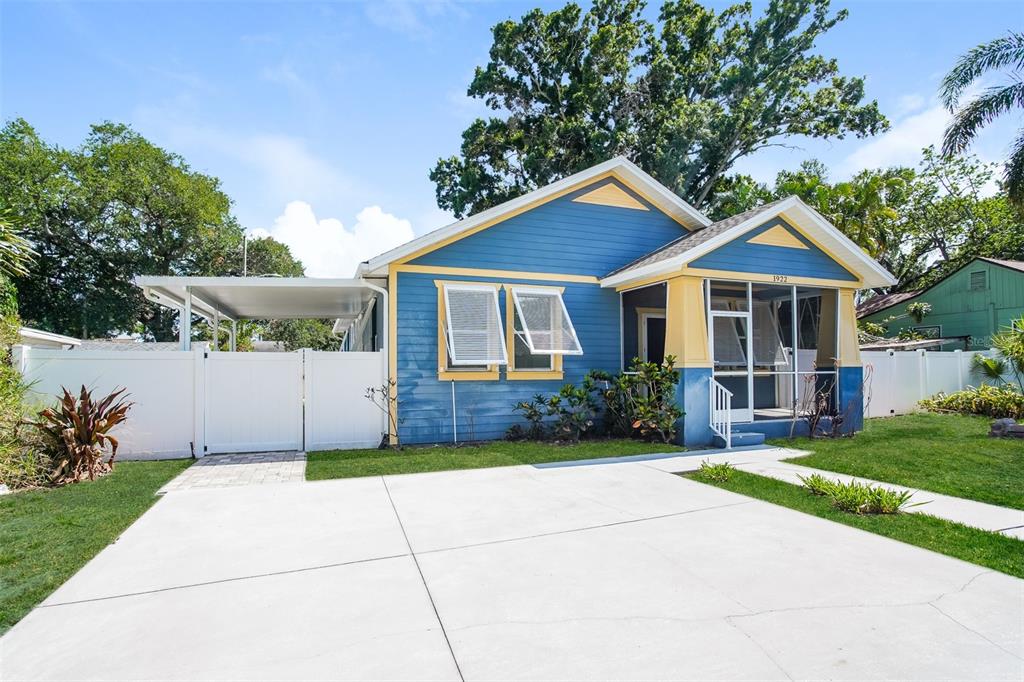 A blue house with yellow trim, a screened front porch, and a white carport — 1922 20TH AVENUE N, ST PETERSBURG, FL