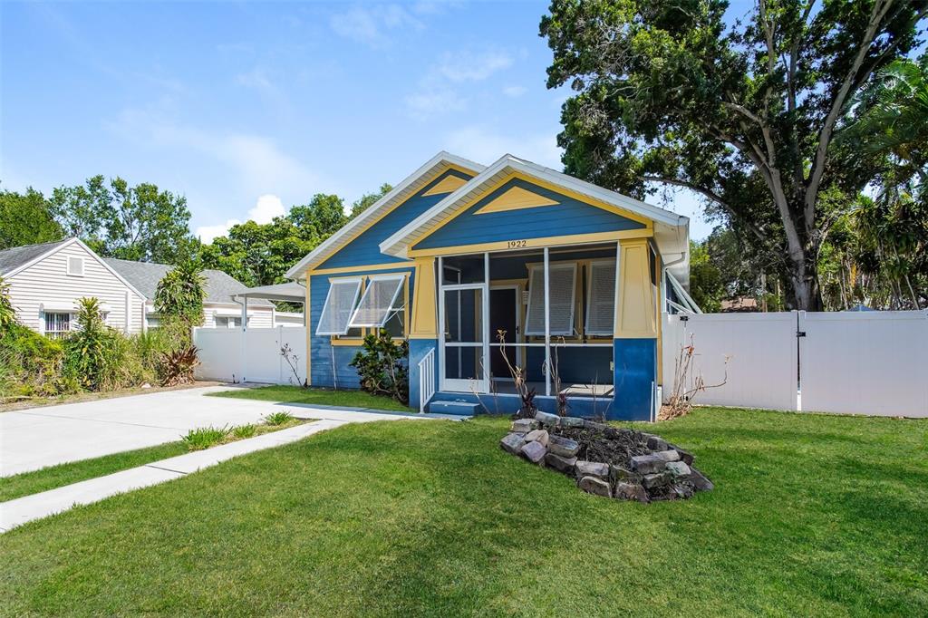 A blue and yellow bungalow with a screened front porch and a stone garden bed — 1922 20TH AVENUE N, ST PETERSBURG, FL