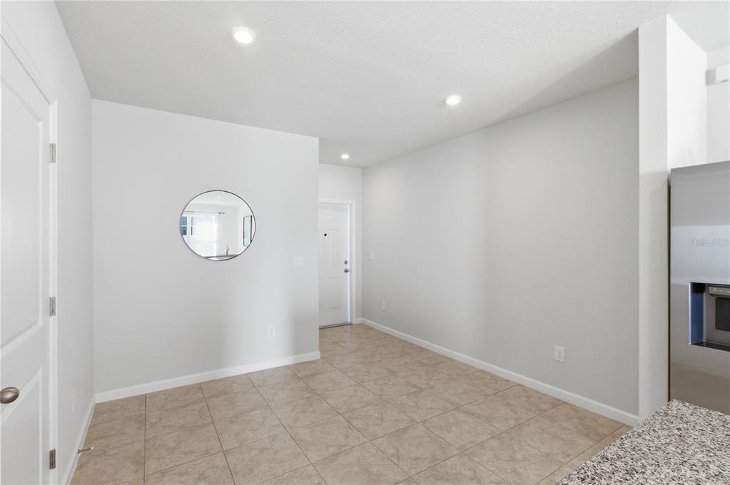An empty dining area features tile flooring, white walls, recessed lighting, and a round mirror — 4740 OLD BLUSH STREET, BRADENTON, FL