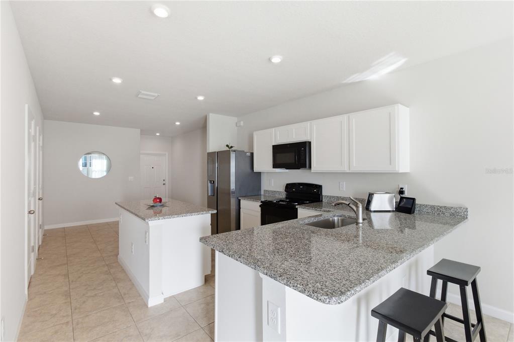 A kitchen features white cabinets, granite countertops, stainless steel appliances, and a central island — 4740 OLD BLUSH STREET, BRADENTON, FL