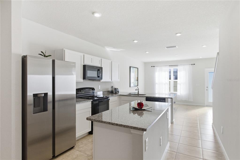A kitchen features white cabinets, granite countertops, stainless steel appliances, and a central island — 4740 OLD BLUSH STREET, BRADENTON, FL