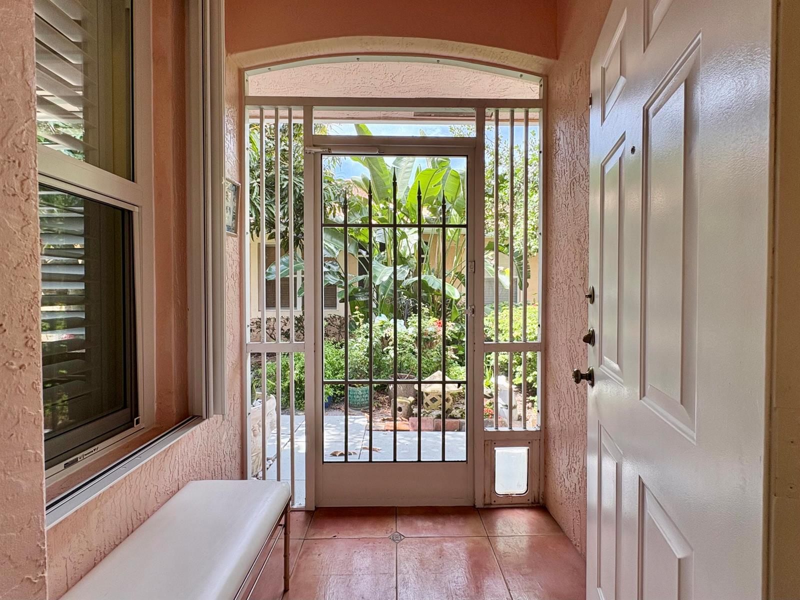 An entryway with a white door, a metal security screen door, and a white bench — 315 Coral Trace Lane, Delray Beach FL 33445, DELRAY BEACH, FL