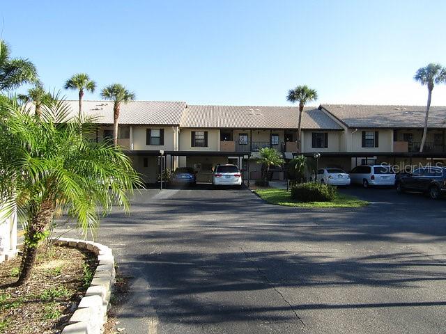 A multi-story apartment building with covered parking and palm trees in front — 255 MISSION TRAIL S UNIT E, VENICE, FL