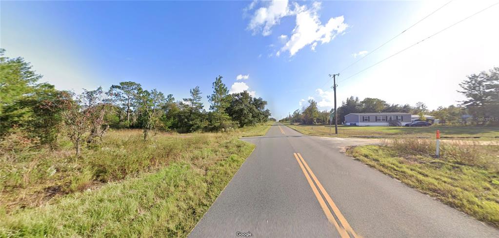 A paved road stretches into the distance past a grassy lot and a mobile home — 1107 LAKEVIEW TRAIL, INTERLACHEN, FL