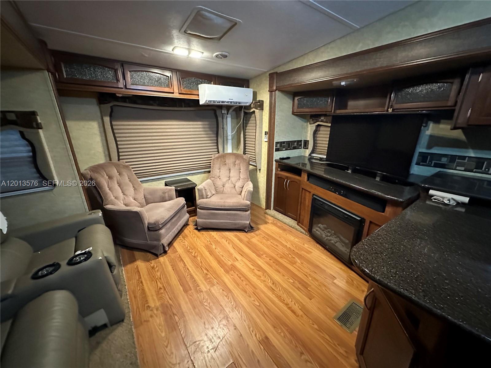 This RV living area features two armchairs, a fireplace, a television, and wood flooring — 9701 SW 77th Ter # 1, Miami FL 33173, MIAMI, FL