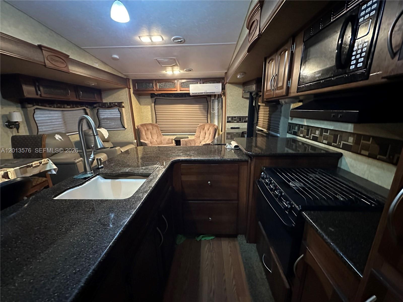A kitchen in an RV features dark granite countertops, wood cabinetry, and a gas stove — 9701 SW 77th Ter # 1, Miami FL 33173, MIAMI, FL
