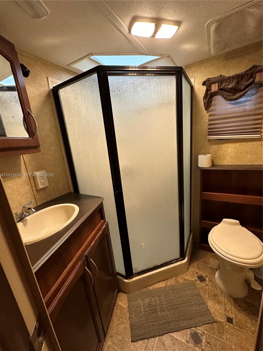 A bathroom in a recreational vehicle features a corner shower, vanity, and toilet — 9701 SW 77th Ter # 1, Miami FL 33173, MIAMI, FL