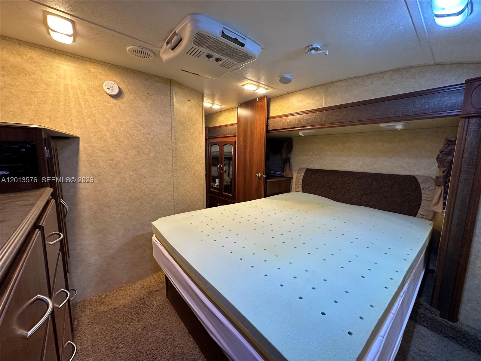 A bedroom in a recreational vehicle features a bed with a foam topper and cabinetry — 9701 SW 77th Ter # 1, Miami FL 33173, MIAMI, FL