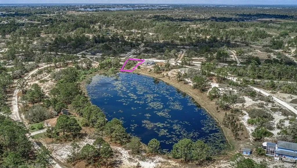 An aerial view shows a vacant lot outlined in pink next to a small lake — 433 GLORIA BOULEVARD, LAKE PLACID, FL